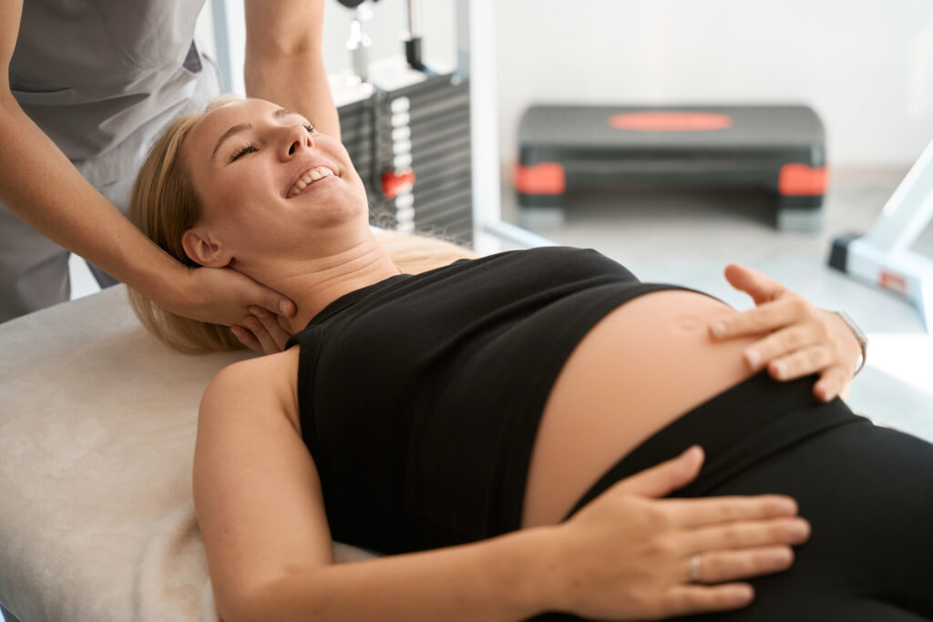 Relaxed pregnant woman receiving neck and back treatment during a prenatal massage with registered massage therapists at Equilibrium Therapeutics in Victoria BC